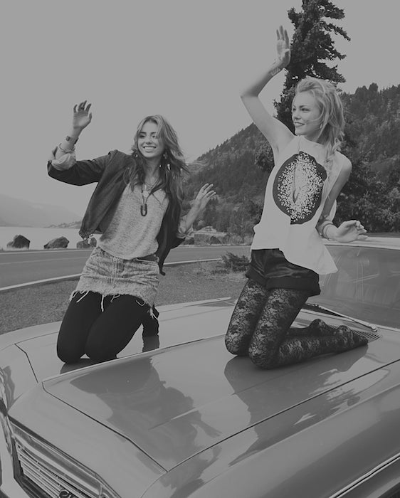 betsy and iya models dancing on top of an antique car.