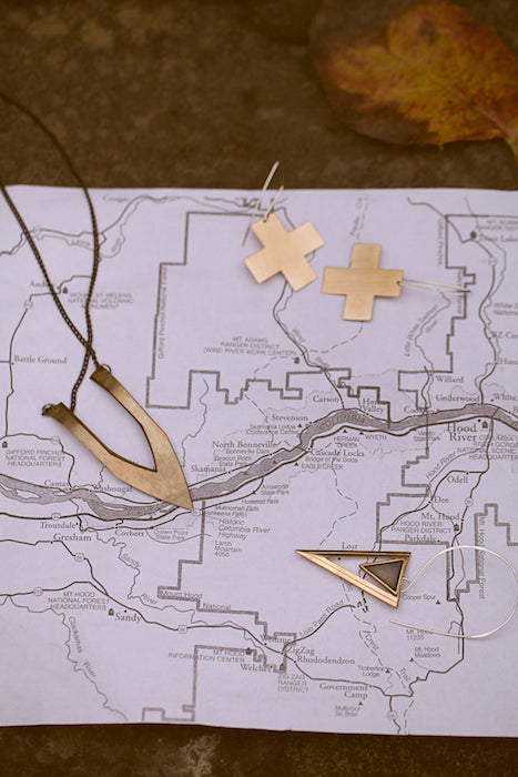 Geometric jewelry pointing to specific places on a map.