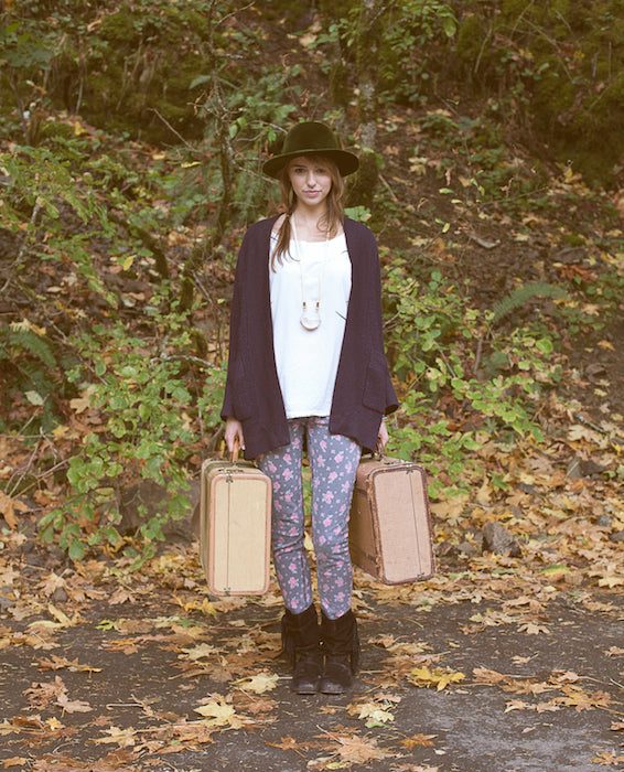A model wearing hip clothing with two suitcases in her hands, ready for an adventure.