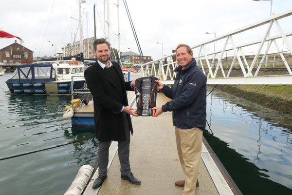 TeamO Marine Design Director Oscar Mead überreicht Philip Warwick, CEO der RNSA Royal Naval Sailing Association, in Gosport eine TeamO BackTow-Rettungsweste. TeamO Marine stellt Rettungswesten für die Besatzung der Corby 29 Cutlass zur Verfügung.