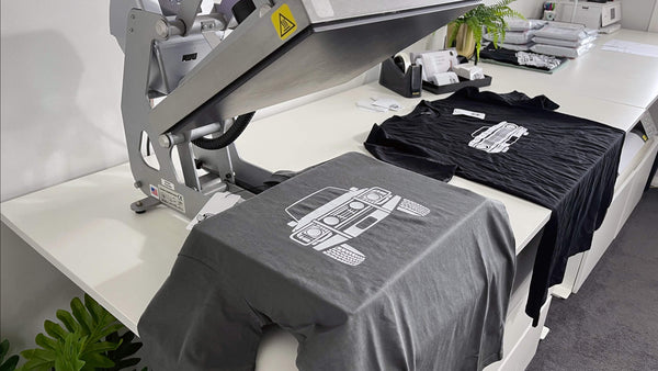 Two t-shirts on a desk with custom printed cars on them.