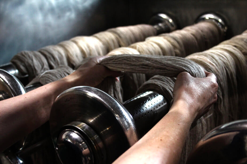 Photo of two hands holding wet yarn that is in process of being dyed.