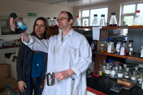 Picture of Rosy and a man in a white coat examining a liquid in a beaker
