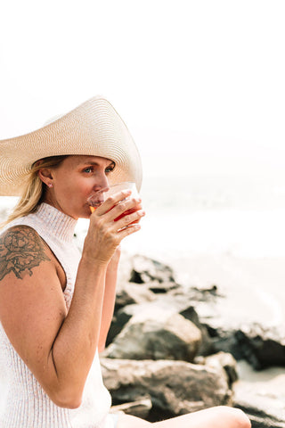 Woman drinking herbal tea by the ocean