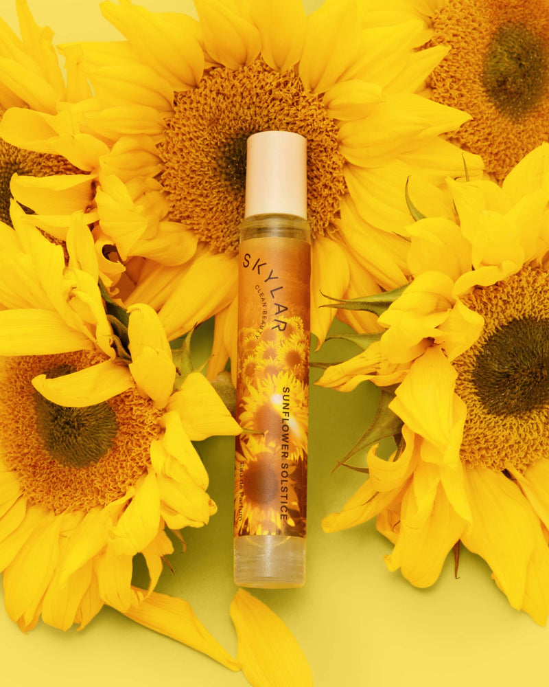 Sunflower Solstice fragrance: Travel-size bottle with a floral citrus scent surrounded by sunflower.