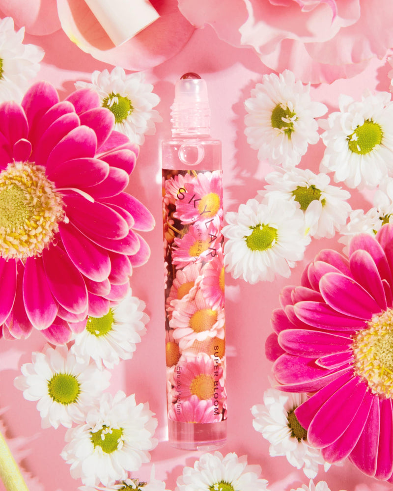 Super Bloom fragrance: Travel-size bottle with a soft floral scent surrounded by flowers.