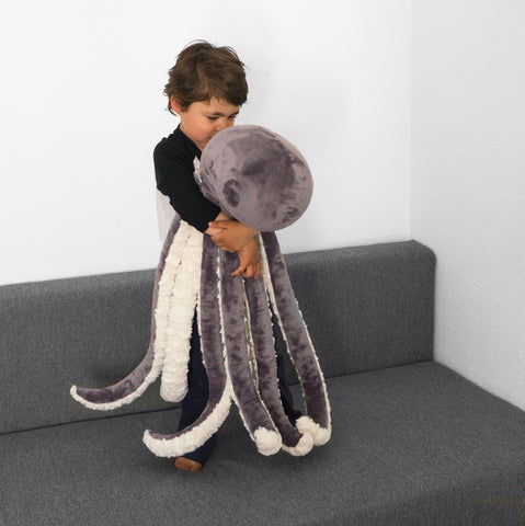 Little kid holding a giant octopus plush toy