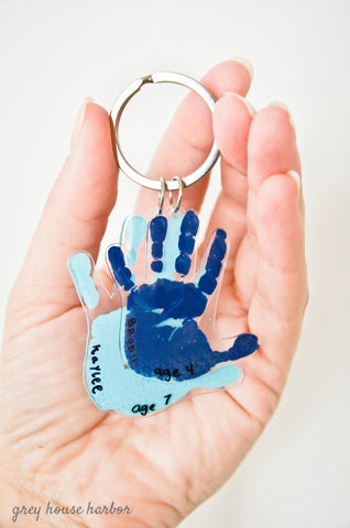 Hand holding a keychain with two hand printed on shrink plastic