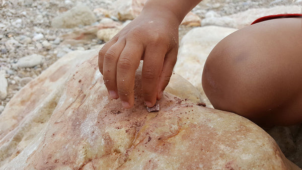Hand of little boy placing a rock on a bigger rock
