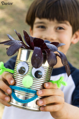 Little kid holding a can planter with arms and smile