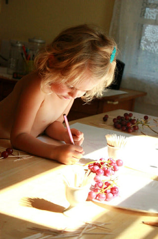 Little girl tracing shadow of a grape
