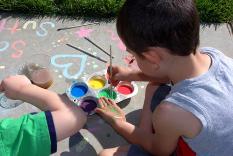 kid painting sidewalk with homemade chalk