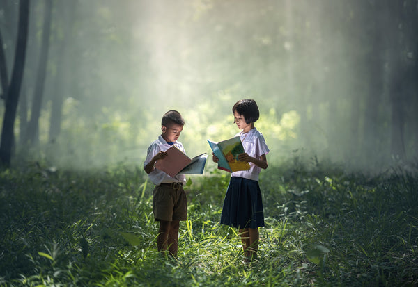 Two kids reading books in the forest