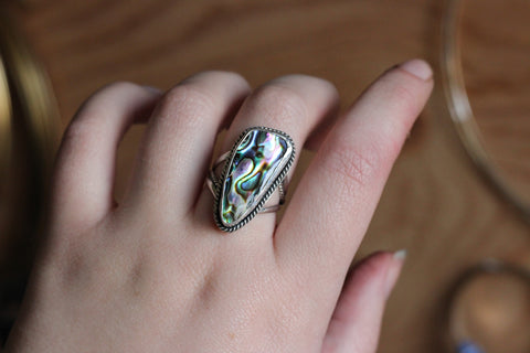 abalone shell set in a sterling silver ring. a smooth strip of silver holds the shell in place.