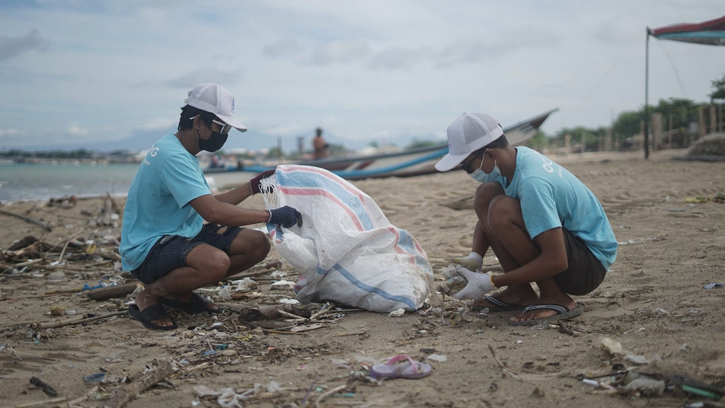 Volunteers help to clean up a beach in Bali. [Image: OCG Saving The Ocean at Unsplash]