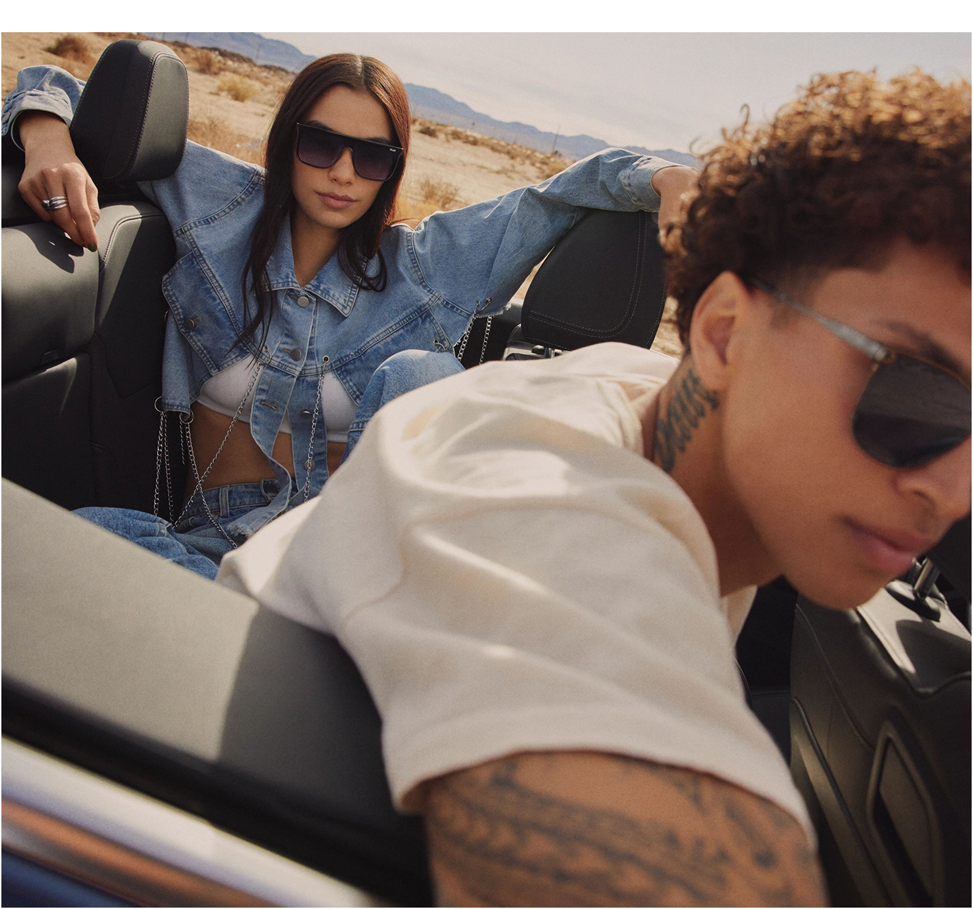 Two models wearing sunglasses in a car