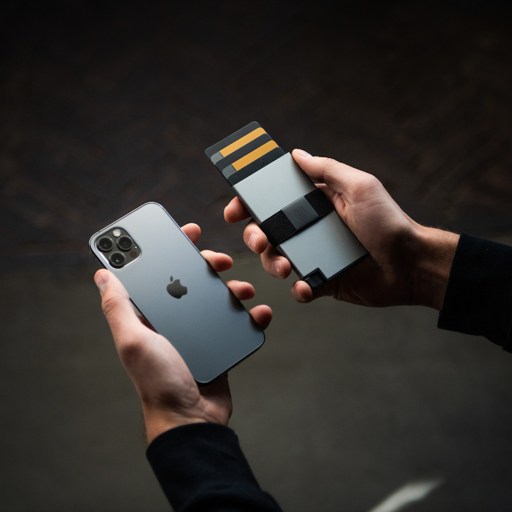 man's hands holding aluminum wallet and iphone