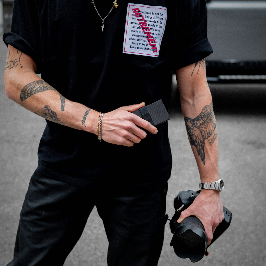 man with tattooed arms holding carbon fiber wallet