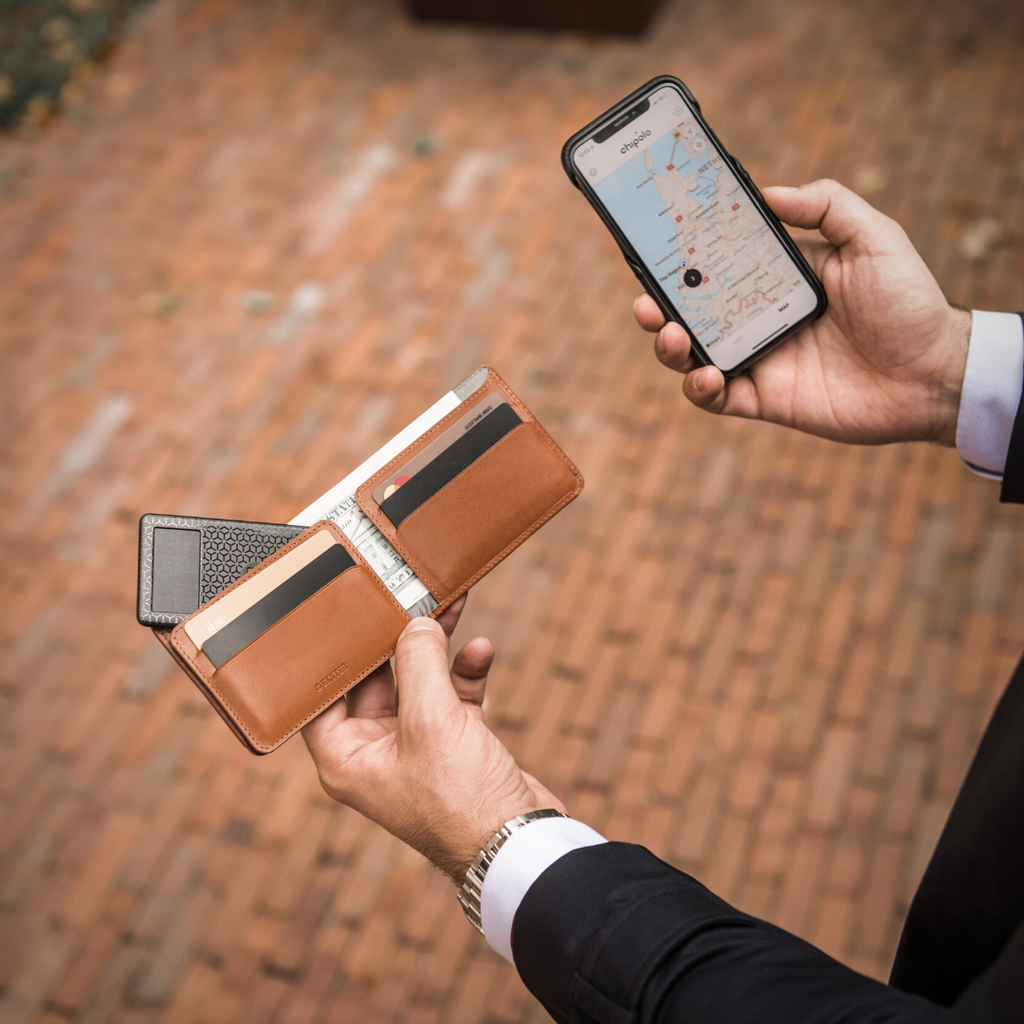 Person’s hands holding an iPhone with Chipolo tracking app and Ekster Bifold wallet with tracker card