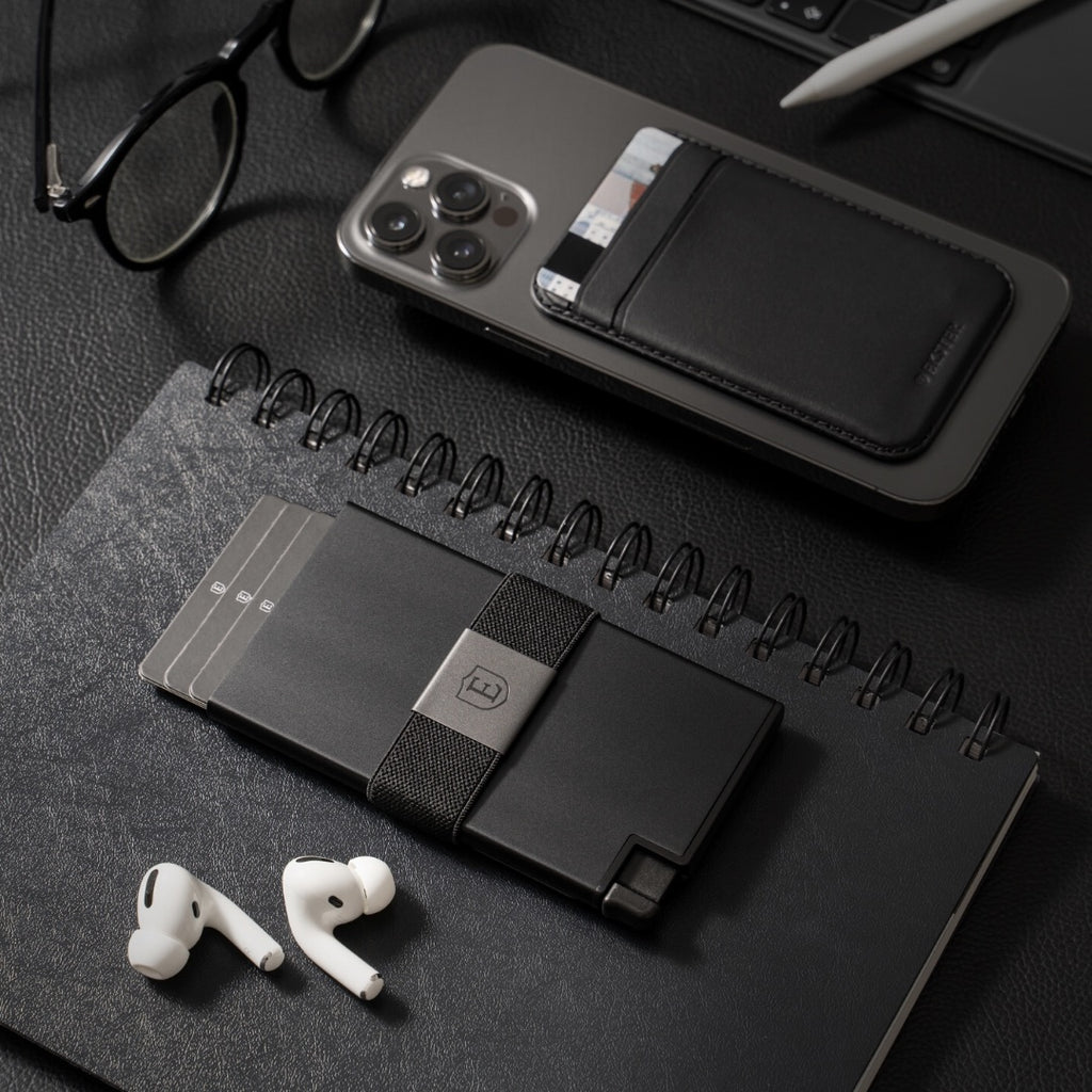 A black Aluminum Cardholder wallet and iPhone with MagSafe Cardholder wallet laying on a desk.