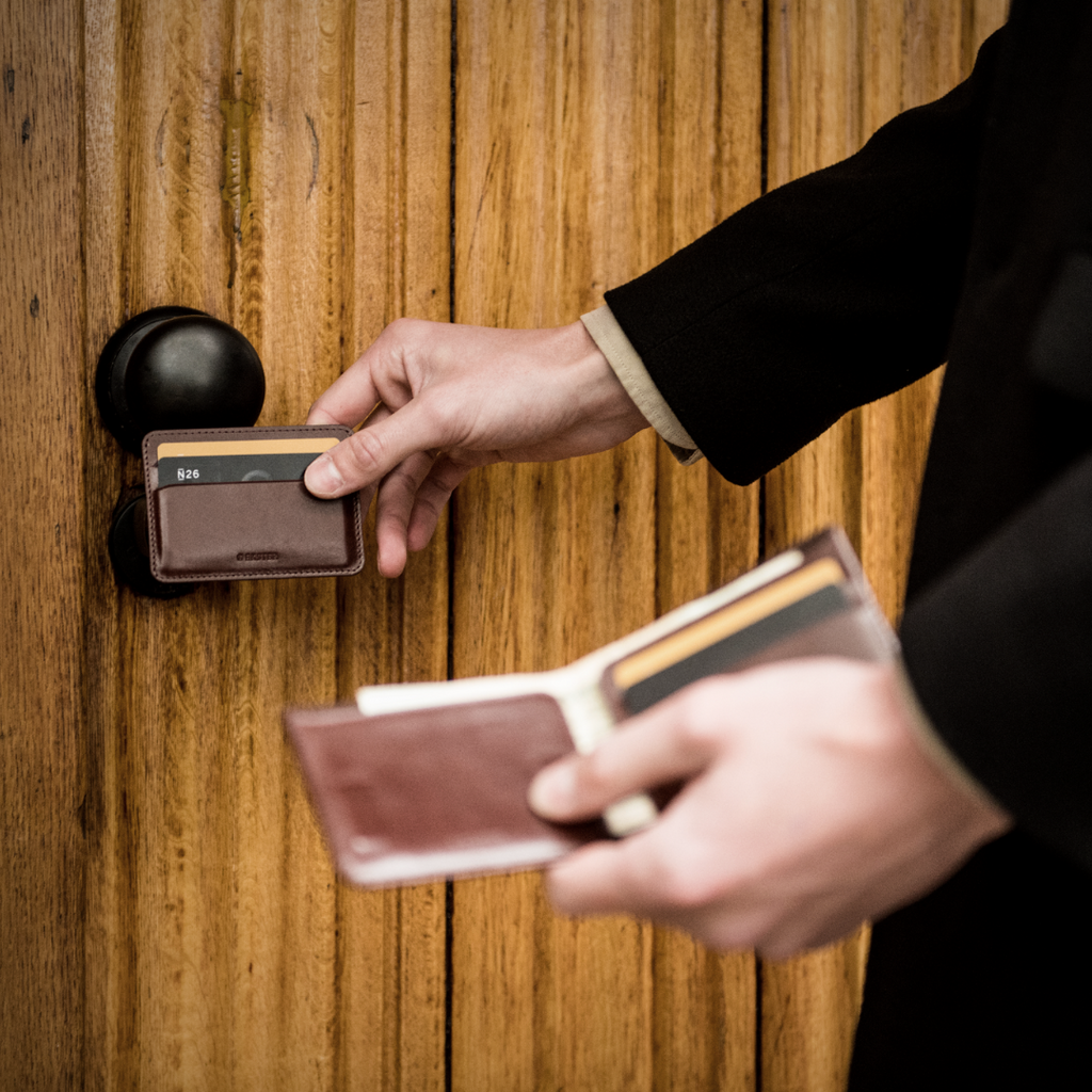 Person's hands holding Ekster Bifold wallet and removable magnetic cardholder to open door
