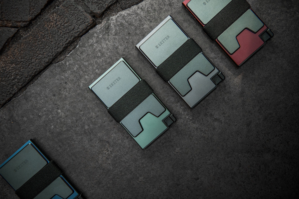 4 aluminum cardholder wallets lying on a grey stone surface.