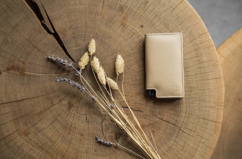 leather pop up wallet in beige color on table next to dried flowers