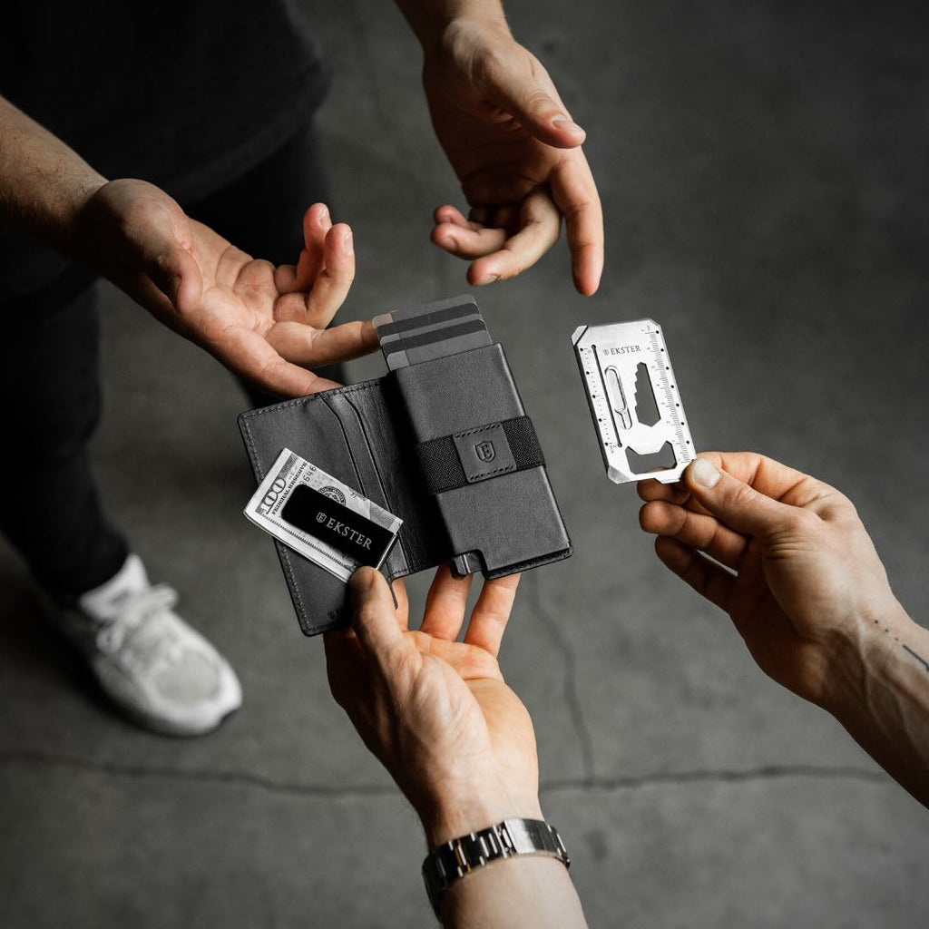 Man's hands holding an Ekster Parliament Wallet with cash clip and tool card.