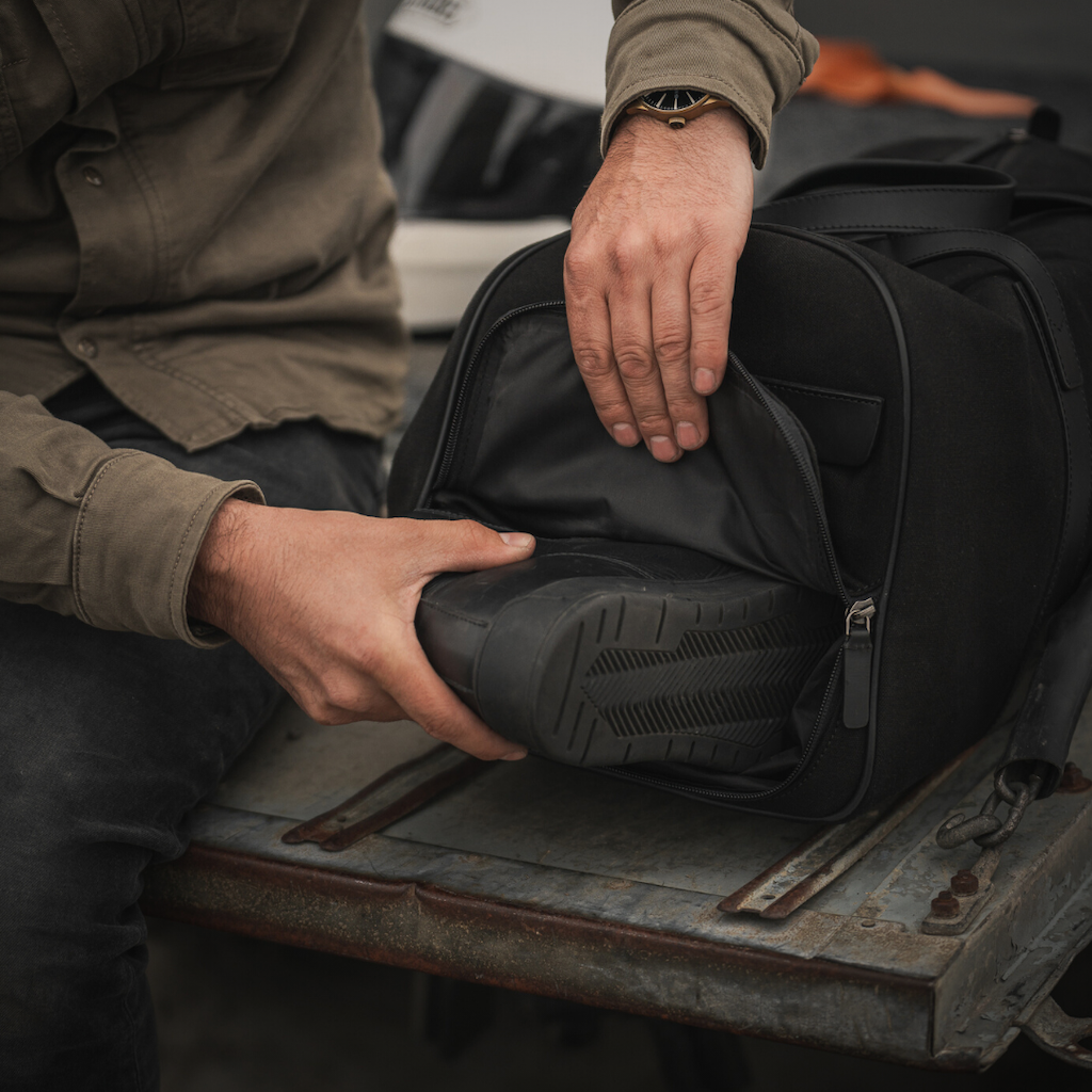 man putting shoes into the shoe compartment of a weekender bag 