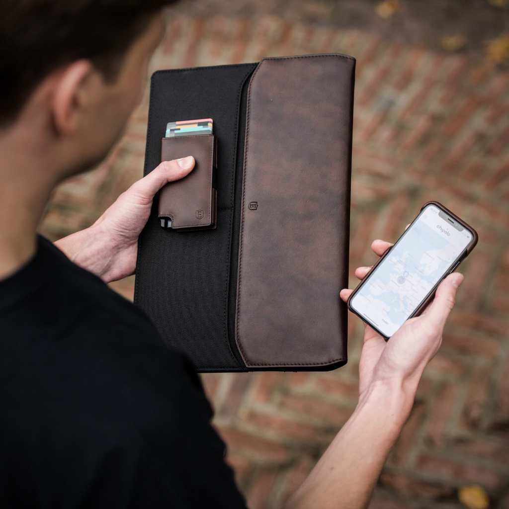 Person holding the Parliament wallet and the Ekster laptop sleeve with an iPhone in the other hand