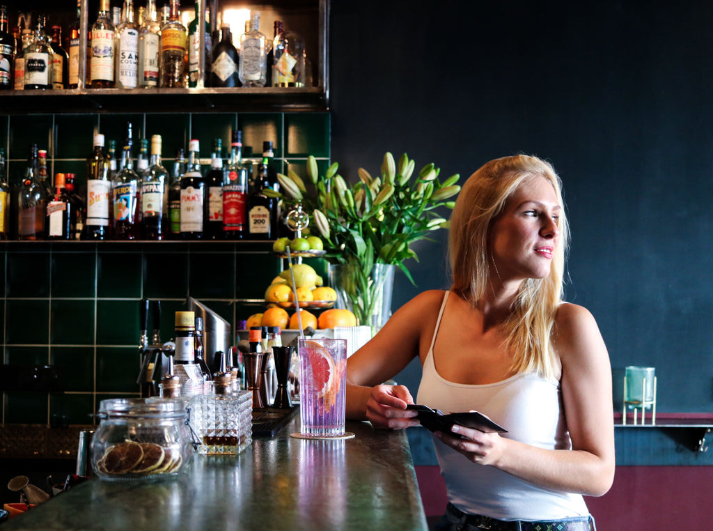 A woman at a bar with her phone wallet and phone