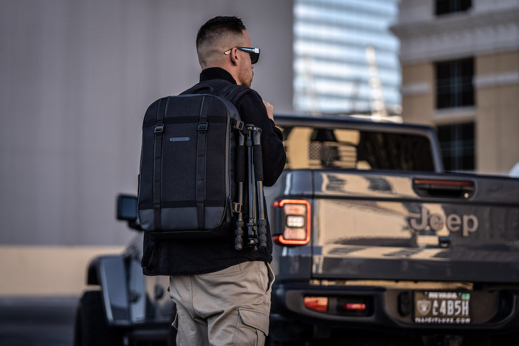 man carrying backpack in front of Jeep truck