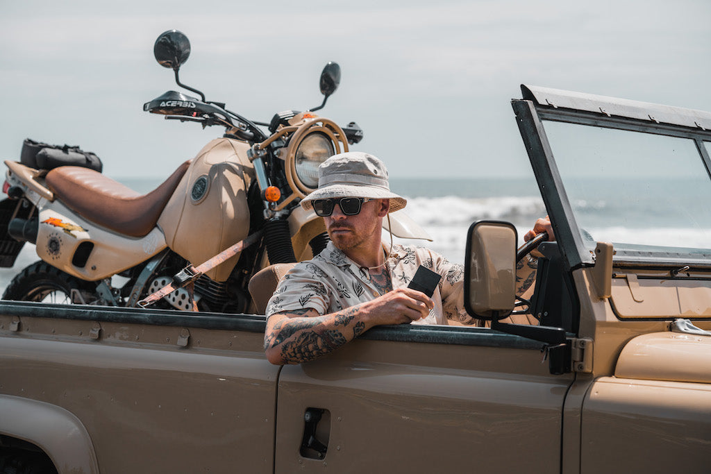 man sitting in car with motorcycle behind