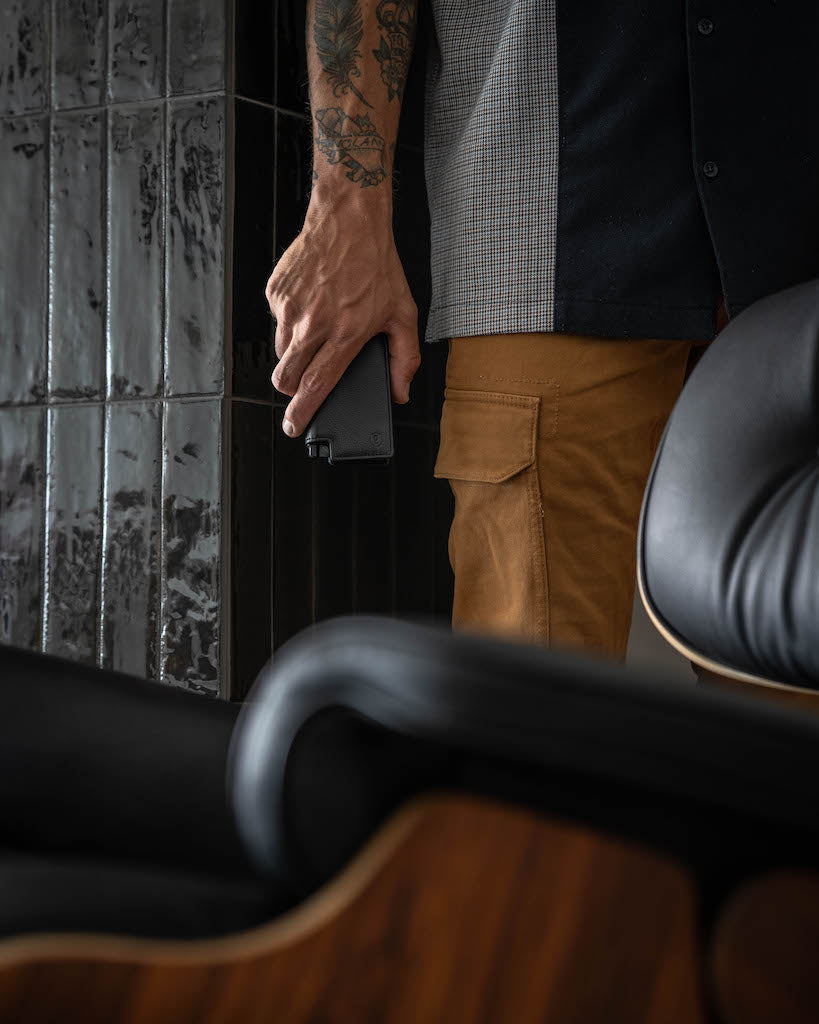 man standing in front of chair holding a leather wallet