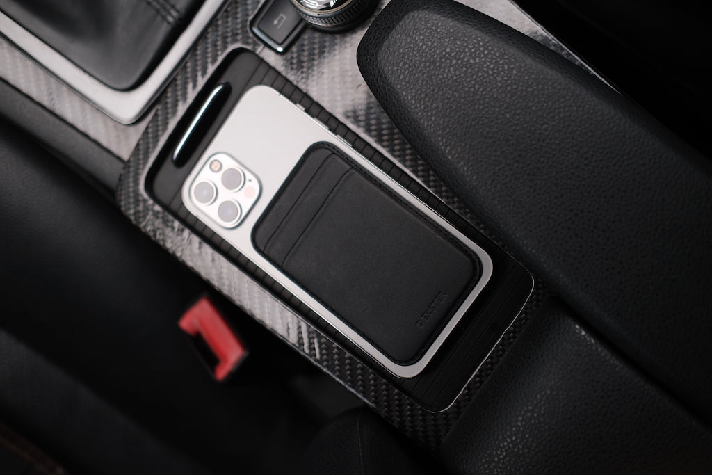 A MagSafe Cardholder attached to the back of an iPhone inside a car.