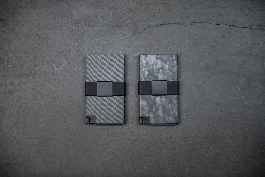 two carbon fiber tactical wallets lying side by side on a concrete surface