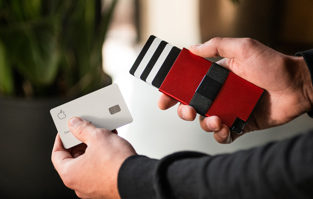 Person’s hand removing credit card from RFID-blocking black red aluminum cardholder
