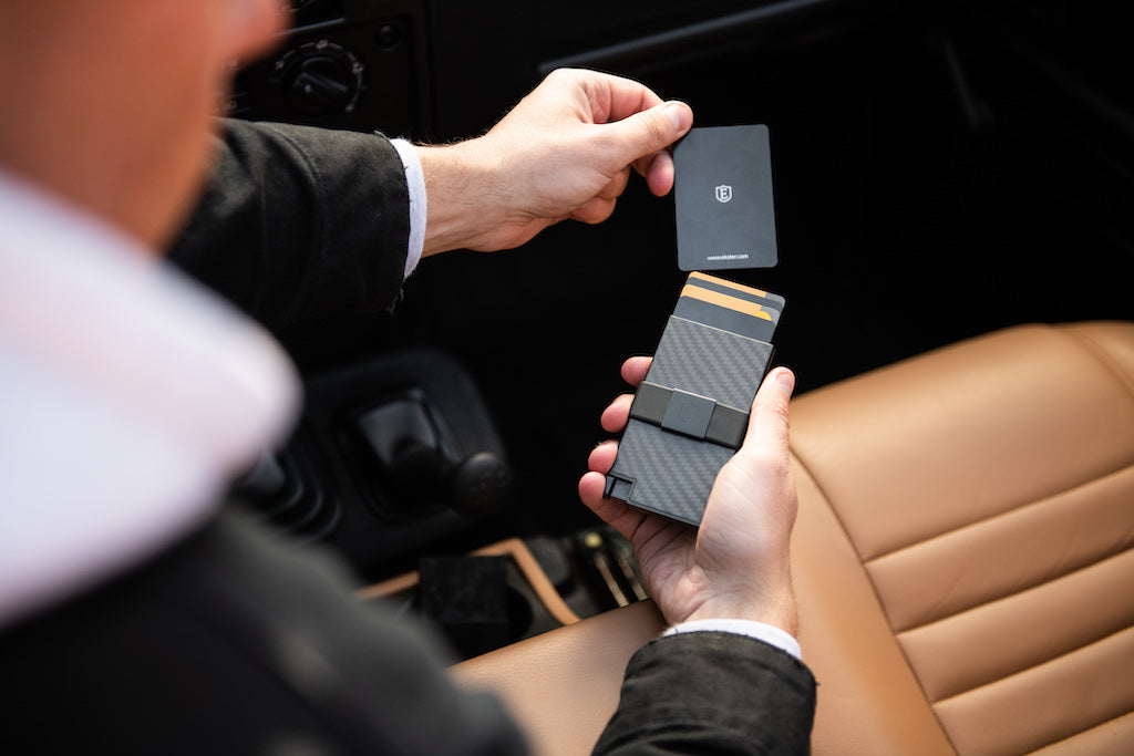 Man removing a card from a carbon fiber card holder wallet. 