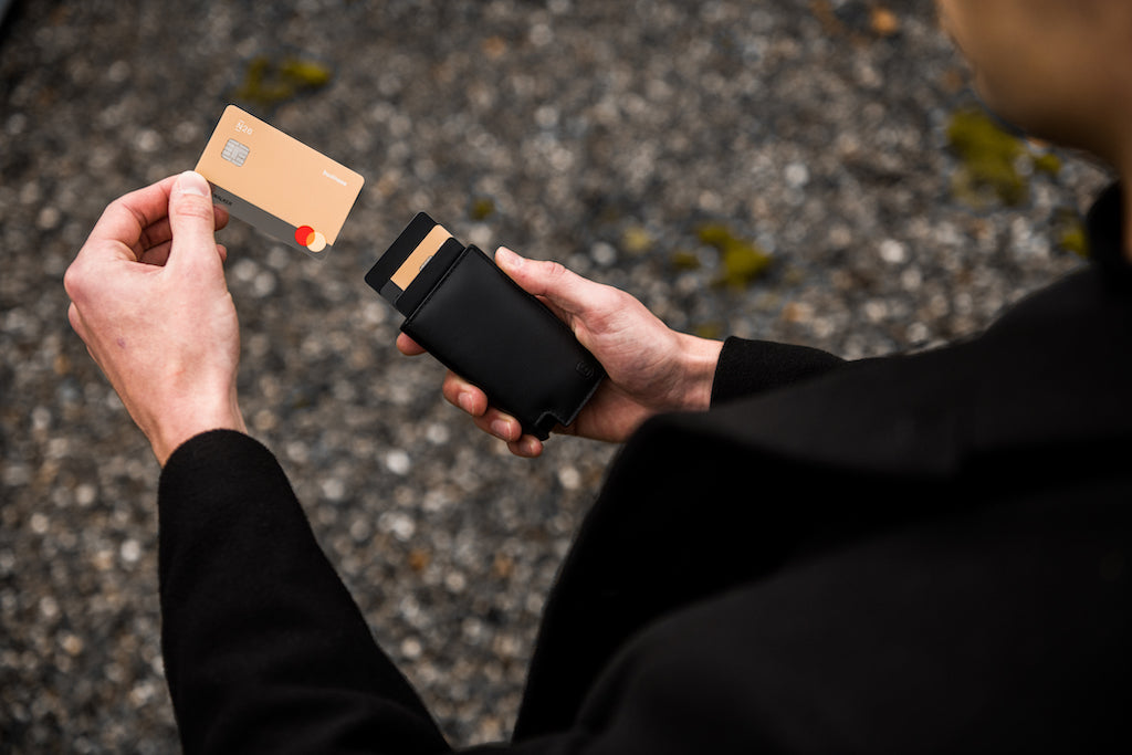 man removing a credit card from a slim black leather wallet 