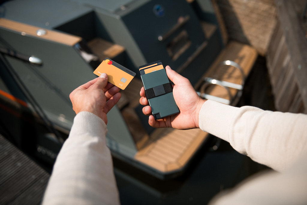 man's hands removing a card from an aluminum tech wallet with tracker