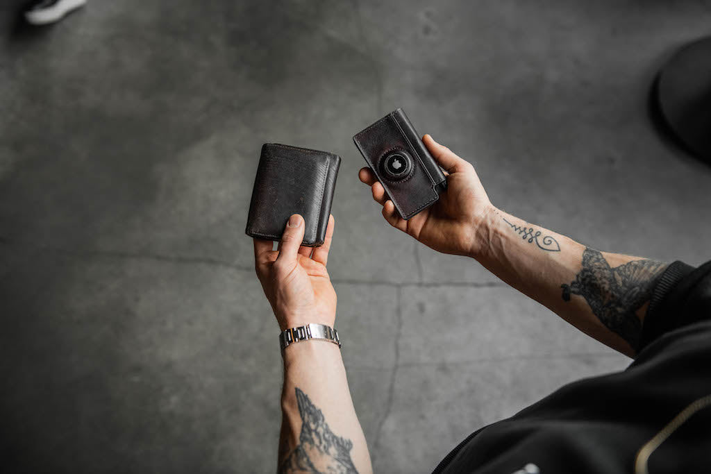 A man comparing two wallets, one is a thick bifold wallet and the other is a much slimmer modern trackable wallet from Ekster.