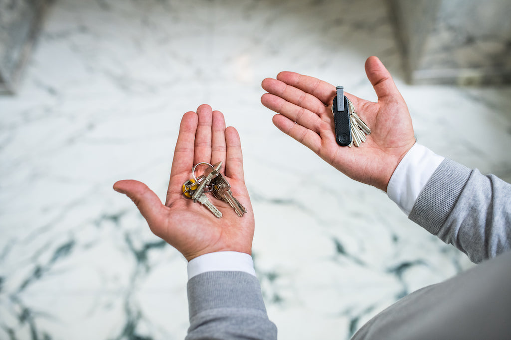 man's hands holding a normal keyring versus an Ekster trackable key organizer