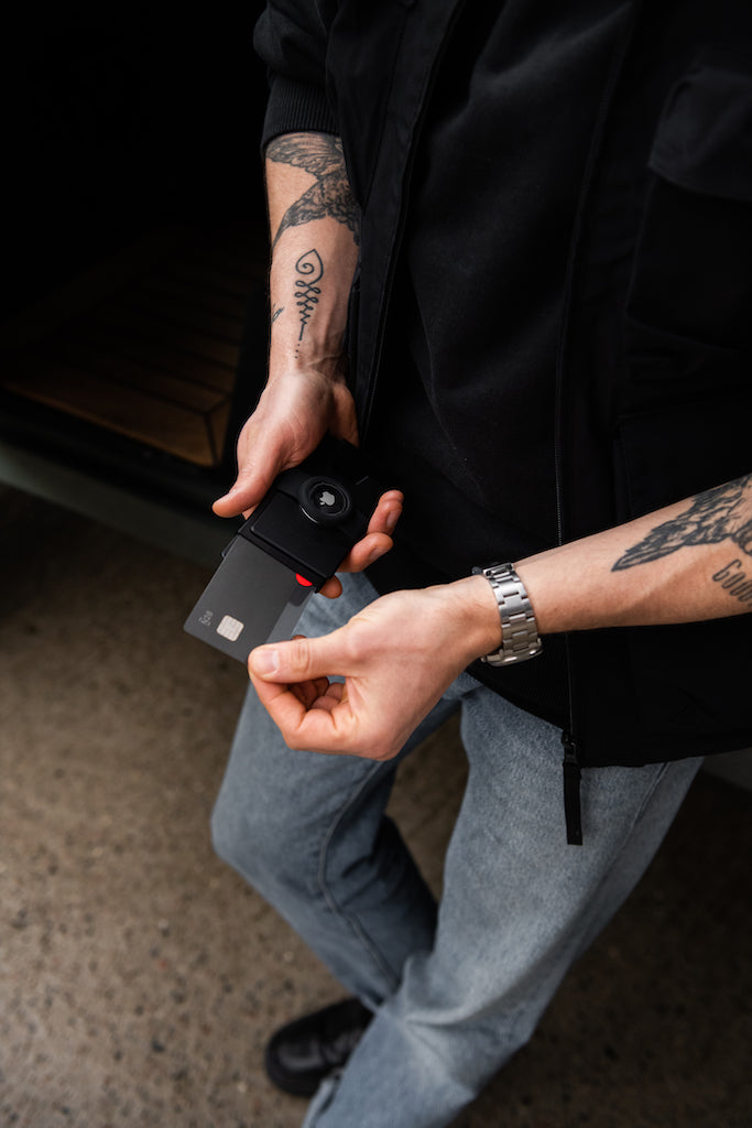 man with tattooed arms taking card out of a wallet