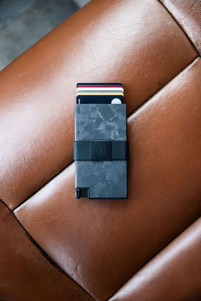 a forged carbon cardholder for airtag lying on a leather seat