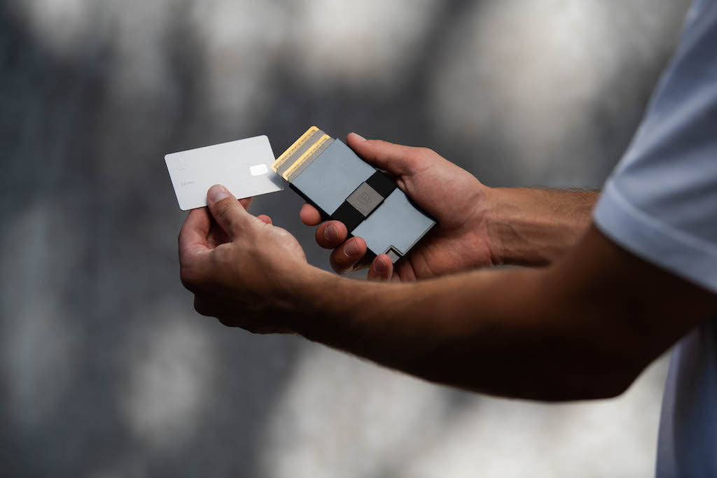 Man taking a card out of a slim metal cardholder wallet. 