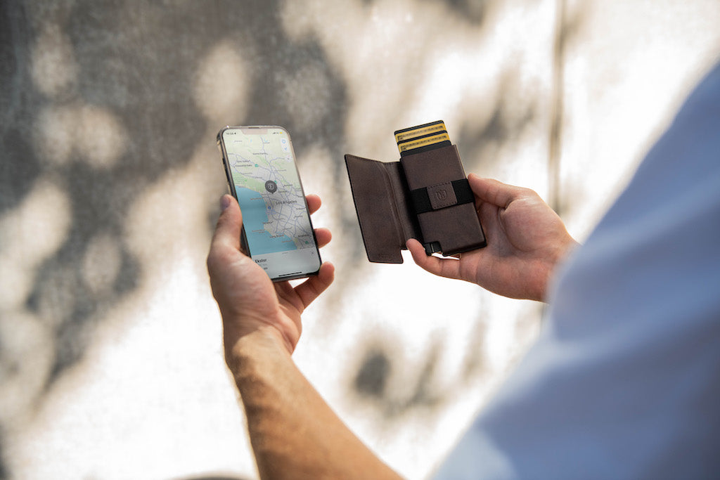 Man holding a card ejector wallet for AirTag in his right hand and an iPhone in his right.