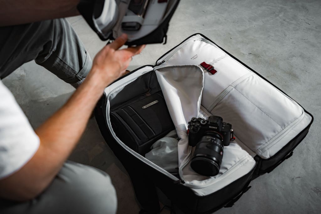 man packing a backpack with camera equipment
