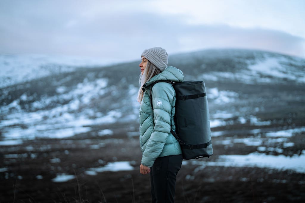 woman wearing travel duffle backpack with snowy background