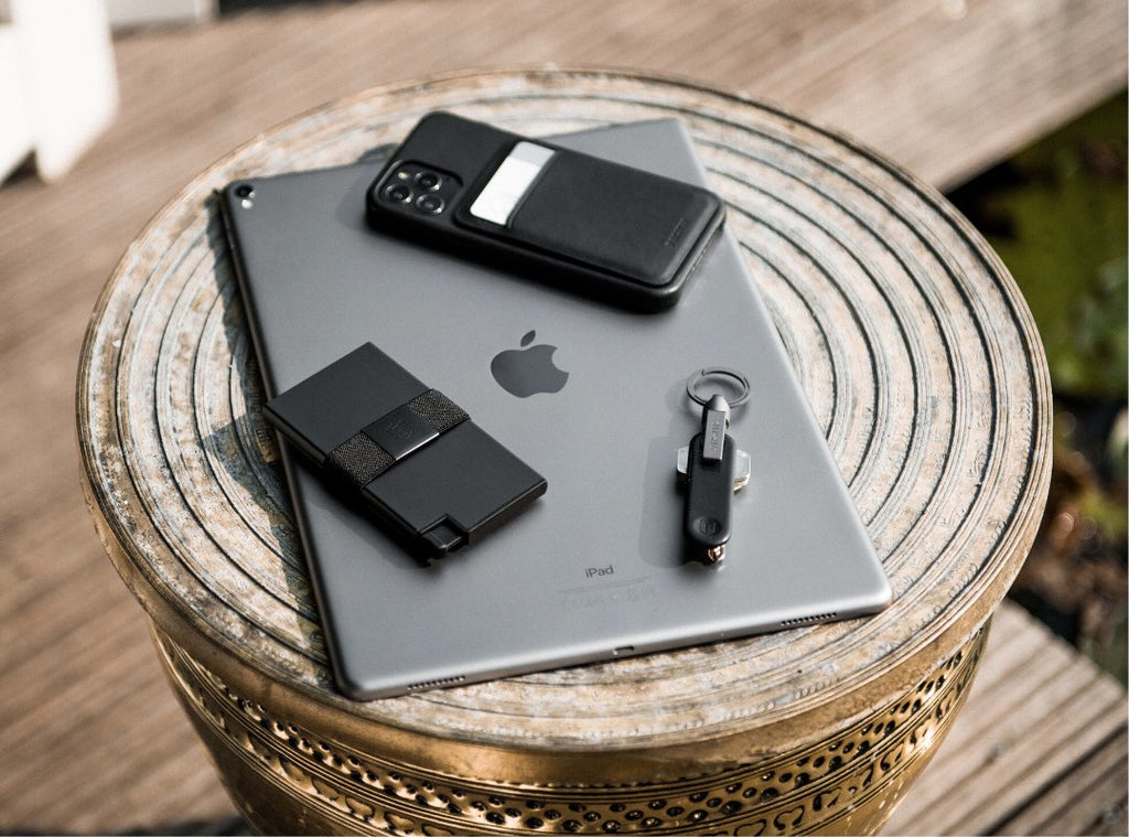 an aluminum cardholder, iPhone, and magnetic keyring on top of an iPad