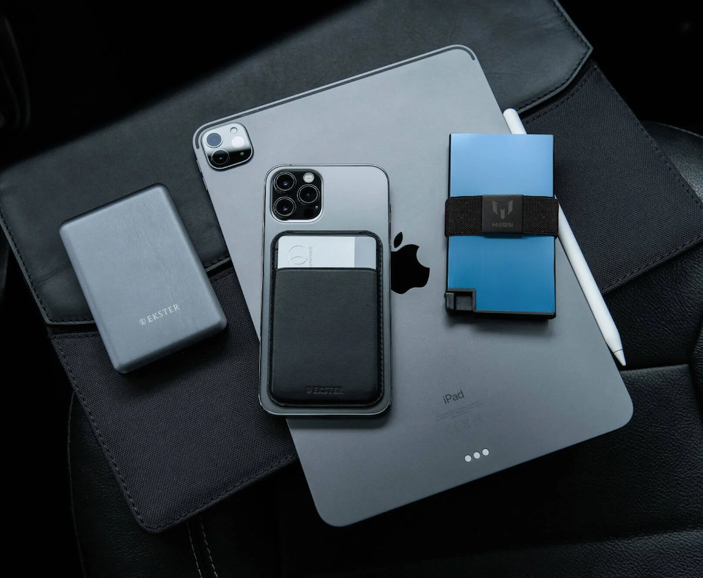 A black MagSafe Cardholder, blue Aluminum cardholder wallet, and power bank lying on top of an iPad.